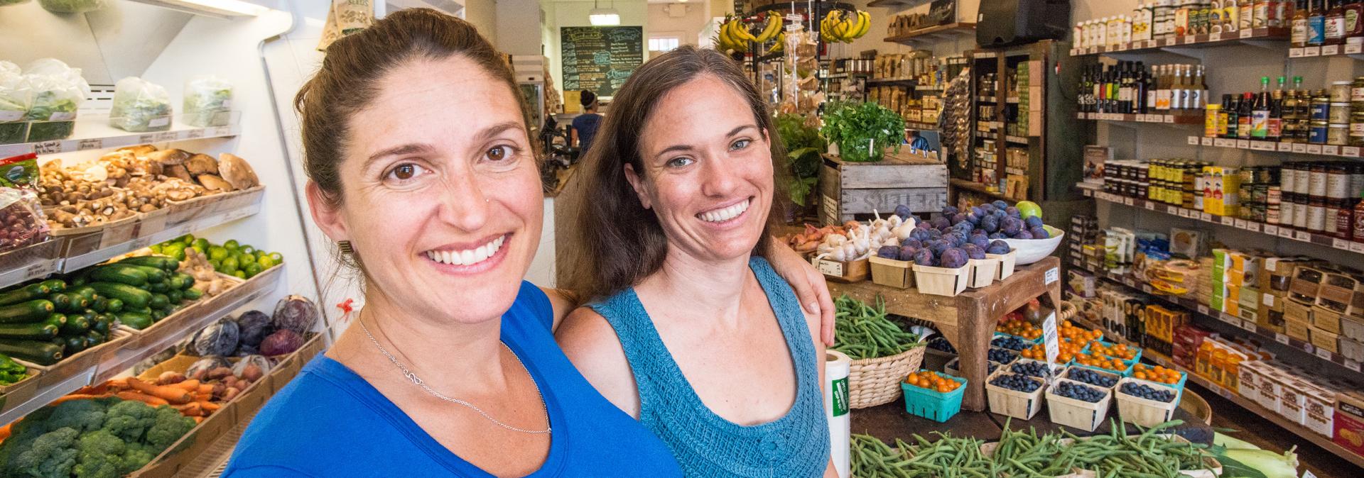 Women smiling in produce section.