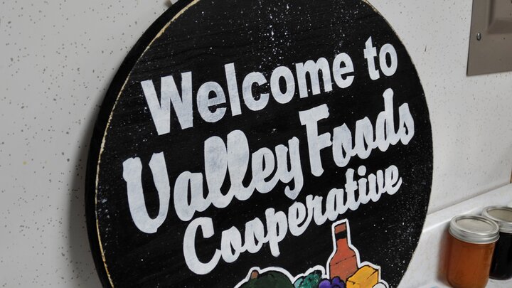 Welcome sign for Valley Foods Cooperative with colorful produce illustration.