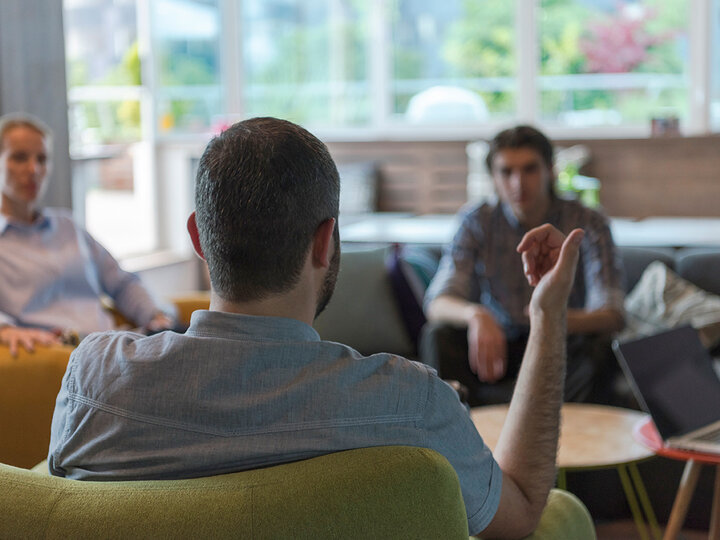 Photo of people sitting in chairs meeting.